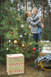 © sofiko14 - Beautiful young mother holding her little son, lokking each other, standing near the decorated Christmas tree and decorations outdoors in winter forest. New Year, Christmas and family concept