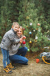 © sofiko14 - Family, young mother and little son, wearing knitted sweaters, decorating fir tree in the forest or park. Colorful decorations, Christmas presents