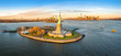 Aerial panorama of the Statue of Liberty in front of Jersey City and New York City skylines at sunset.
