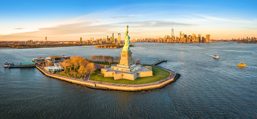 Fototapete - Aerial panorama of the Statue of Liberty in front of Jersey City and New York City skylines at sunset.