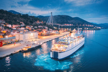 Aerial View Of Cruise Ship In Port At Night. Landscape With Ships And Boats In Harbour, City Lights, Buildings, Mountains, Blue Sea At Sunset. Top View. Luxury Cruise. Floating Liner At Harbor In Dusk