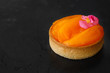 Fruit tart with persimmon on a black background. Fresh bakery.