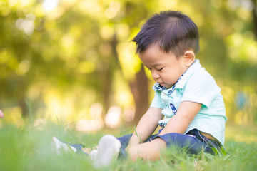 Adorable smart baby boy playing in city green park