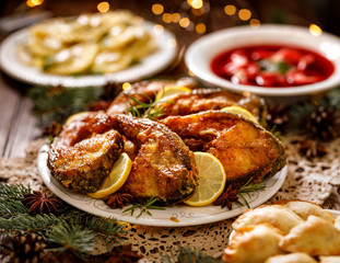 Wall Mural - Christmas carp, fried carp fish slices on a ceramic plate on the holiday table, close up. Traditional christmas eve dish. Polish Christmas