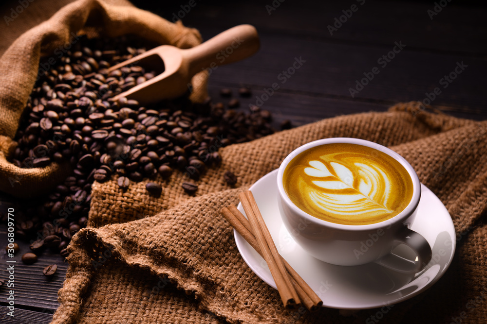 Cup of coffee latte and coffee beans in burlap sack on old wooden background - obrazy, fototapety, plakaty 