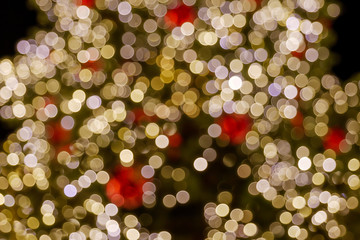 Wall Mural - Gold and red Christmas light shiny abstract round bokeh on black background. Colourful Glitter bokeh from blurry decoration bulbs.