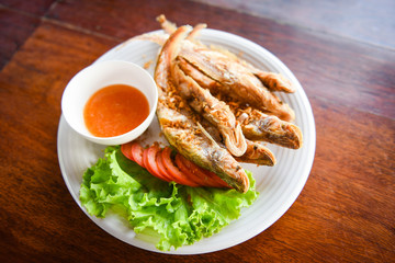 Wall Mural - fried fish with vegetable salad tomato and sauce on white plate wooden table / freshwater fish Mekong River Other names Sheatfishes Siluriformes Siluridae