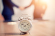© PRASERT - Alarm clock on  table with business people  in seminar room. Meeting corporate success brainstorming teamwork