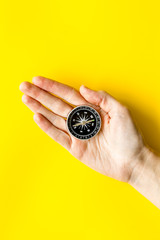 Wall Mural - Choose direction concept. Compass in hand on yellow background top view copy space
