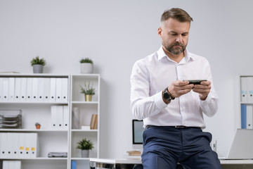 Aufkleber - Serious office worker in formalwear watching video in smartphone or messaging