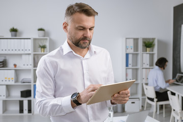 Aufkleber - Serious employer in formalwear using touchpad to find information by workplace
