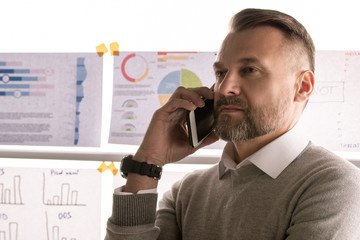 Aufkleber - Confident mature broker holding smartphone by ear while talking to client