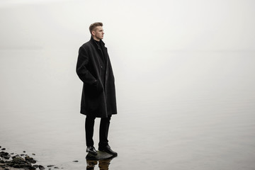 young man in coat autumn sea fog