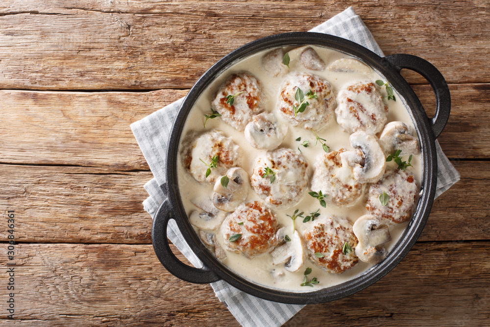 Main dish of meatballs with mushrooms served in creamy cheese sauce with thyme close-up in a pan. horizontal top view - obrazy, fototapety, plakaty 
