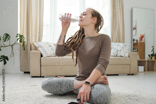 уставшая женщина пьет воду на диване