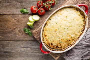 Sticker - Casserole with chicken and zucchini on old wooden background, top view