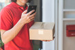 © Pormezz - Delivery man looking customer address in mobile application. Selective focus on hand.