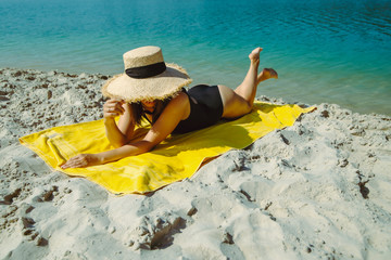 woman laying on yellow blanket sunbathing at sand beach