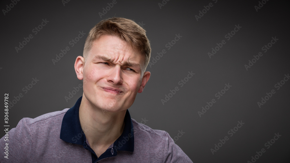 A young man grimaces in pain - obrazy, fototapety, plakaty 