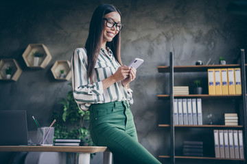 Photo of cheerful positive boss of corporation having rest spending free time on social media smiling toothily leaning on desktop in spectacles green pants