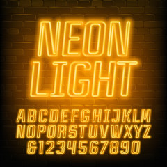 Fototapete - Neon alphabet font. Yellow neon geometric letters and numbers. Brick wall background. Stock vector typescript for your typography design.