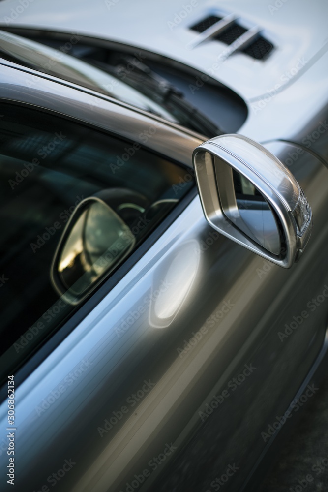 Vertical high angle shot of the side mirror of a beautiful silver car - obrazy, fototapety, plakaty 