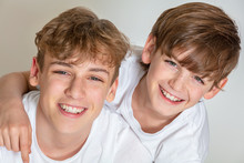 White Background Studio Photograph Of Young Happy Boy Children Brothers Wearing T-shirts And Smiling Together With Perfect Teeth