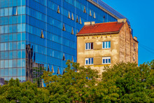 View Of An Old Aged Building Standing Next To A New Modern With A Glass Facade. Image