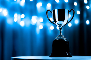 silver trophy competition in the dark on the abstract blurred light background with copy space, blue