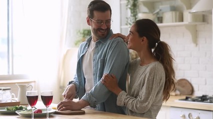 Wall Mural - Cheerful young couple cook together prepare healthy meal in kitchen