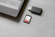 SD Memory Card On Table Beside Laptop Computer And Card Reader