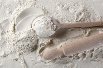 Wheat flour with wooden spoon and kitchen roller, background and texture