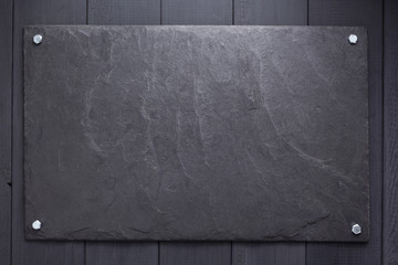 Wall Mural - slate stone nameplate or wall sign at wooden background