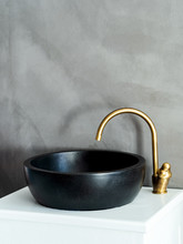 Black Sink, Vintage Copper Faucet, Gray Concrete Surface Wall, Round Mirror, Loft Bathroom Interior Details. Minimalist Concept Interior Details.