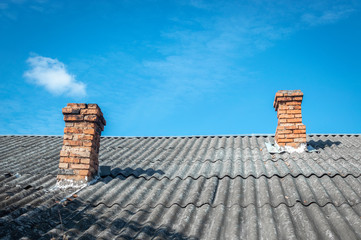 Two brick chimneys on an asbestos-slate roof, view up against the sky. Typical Roofs in Eastern Europe