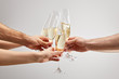cropped view of men and women toasting while holding champagne glasses with sparkling wine isolated on grey