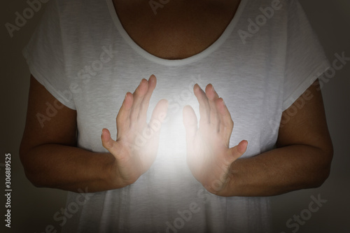 Healer demonstrating how to sense the human electromagnetic with hands - concept - woman in a white top with hands cupped around a white ball of energy