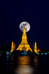 Wat Arun Temple at night with full Moon in Bangkok Thailand.Photo by long exposure.