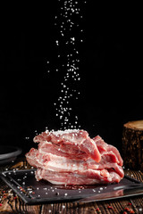 Raw pork meat lies on a cutting board, on a wooden table, next to a kitchen knife. Pickled meat in spices. Background image.