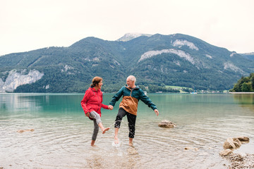 Sticker - A senior pensioner couple hikers standing barefoot in lake in nature.