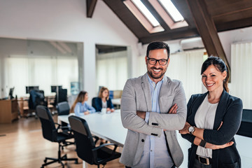 Wall Mural - Portrait of two business partners standing with arms crossed in meeting room.