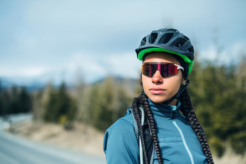 Female mountain biker standing on road outdoors in winter nature.