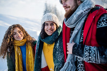 Group Of Cheerful Young Friends Outdoors In Snow In Winter Forest, Talking.