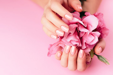 Beautiful Woman Hands with fresh eustoma. Spa and Manicure concept. Female hands with pink manicure. Soft skin, skincare concept. Beauty nails. Over beige background