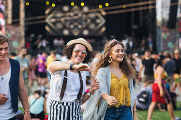 Wall Mural - Front view portrait of group of young friends dancing at summer festival.