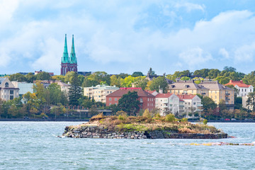 Wall Mural - Helsinki. Finland. Panorama of Helsinki from the water. An island in the Harbor. Spires of St. John's Church in Helsinki. Houses on the waterfront. Baltic sea. Trip to Finland.