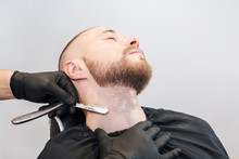 Barber's Hand With A Razor Shaves A Beard On The Patient's Throat.