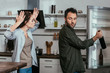 © LIGHTFIELD STUDIOS - Woman quarreling while husband taking wine bottle from fridge