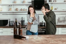 Selective Focus Of Angry Man Quarreling With Alcohol Addicted Wife On Kitchen