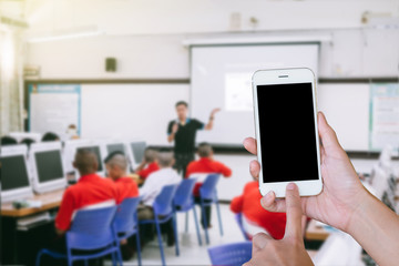 Wall Mural - Hands woman are holding touch screen smart phone,tablet on blurred classroom computer with student and teacher background.